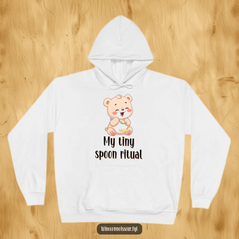 Funny hooded sweatshirt with a giggling bear cub playfully tasting a tiny drop of honey from a miniature spoon, radiating pure happiness.